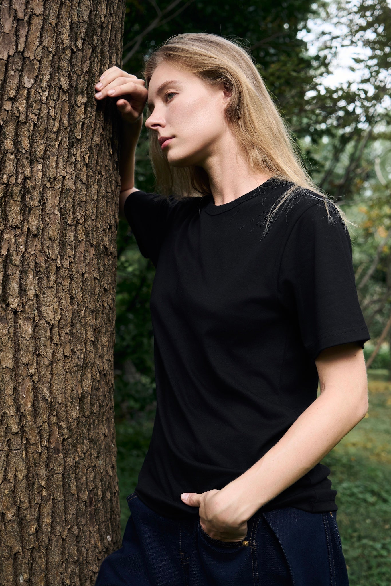 Female model confidently and attentively gazing, wearing AURETEMPHE black organic cotton short sleeve t-shirt.