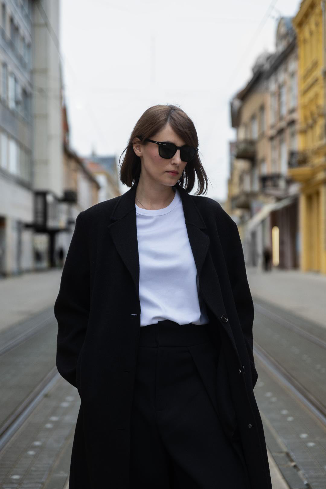 A person wearing a white organic cotton unisex T-shirt by AURETEMPHE, styled in a minimal and modern look