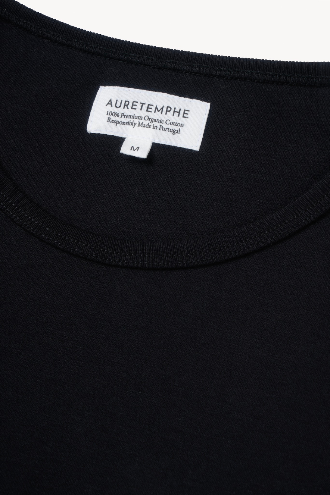 Detail view of AURETEMPHE black long sleeve t-shirt featuring its organic cotton main label.