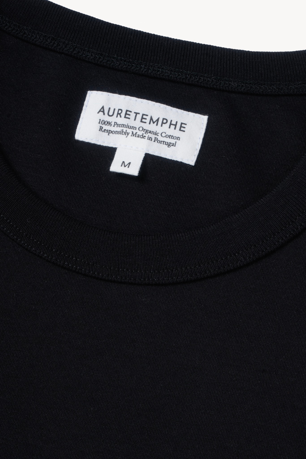 Detail view of AURETEMPHE black short sleeve t-shirt featuring its organic cotton main label.