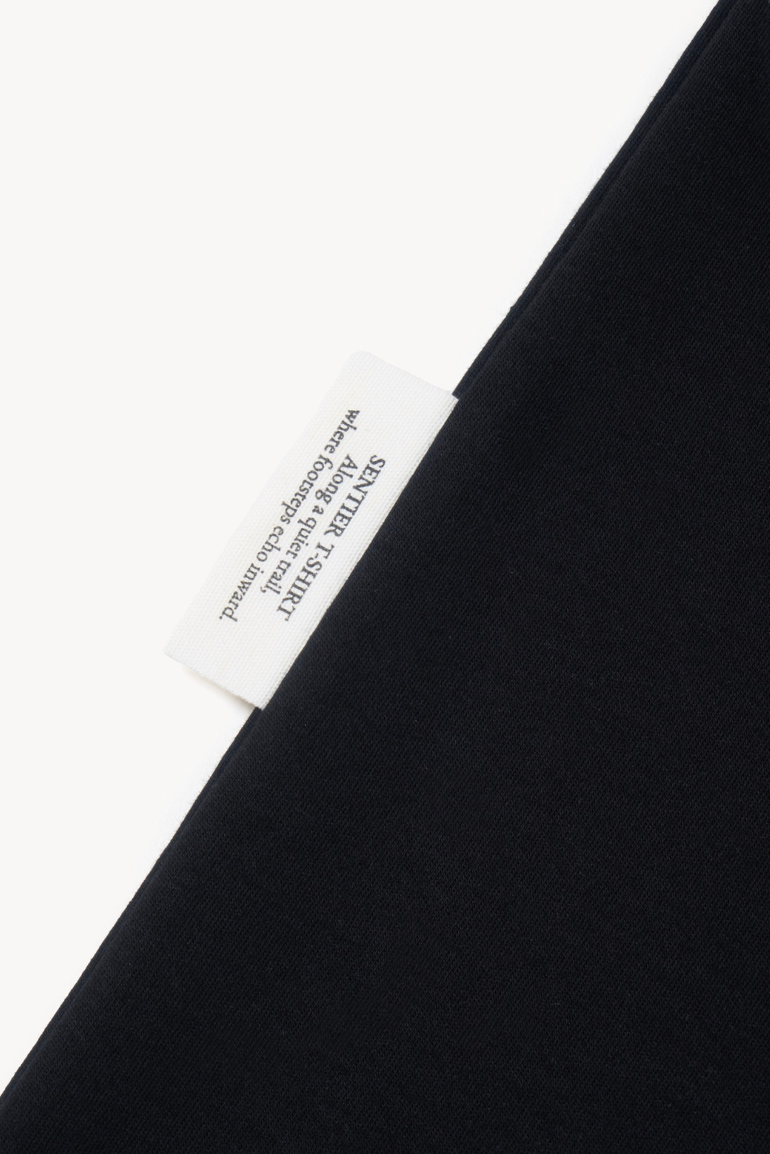 Detail of AURETEMPHE black short sleeve t-shirt showing its organic cotton side label.