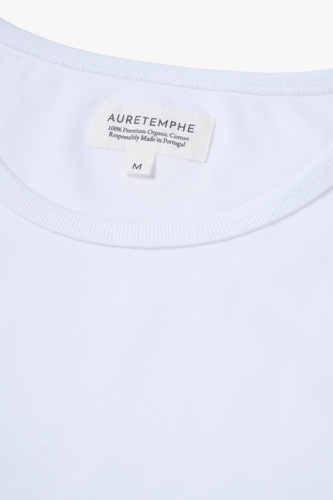 Detail view of AURETEMPHE white long sleeve t-shirt featuring its organic cotton main label.