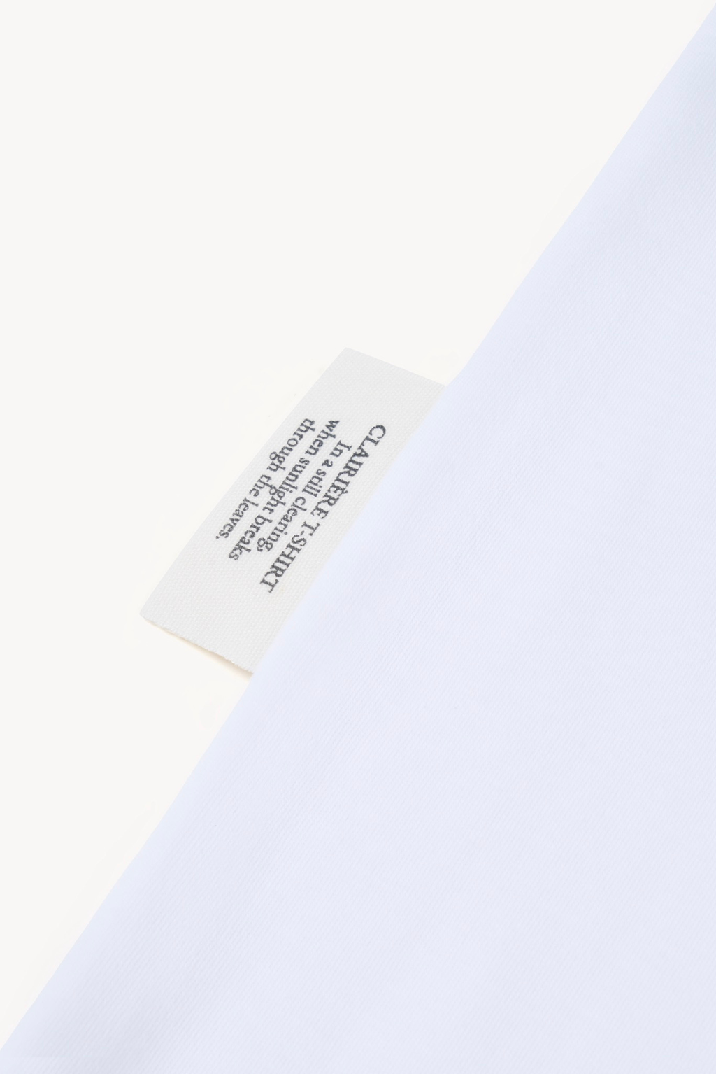 Detail of AURETEMPHE white long sleeve t-shirt showing its organic cotton side label.