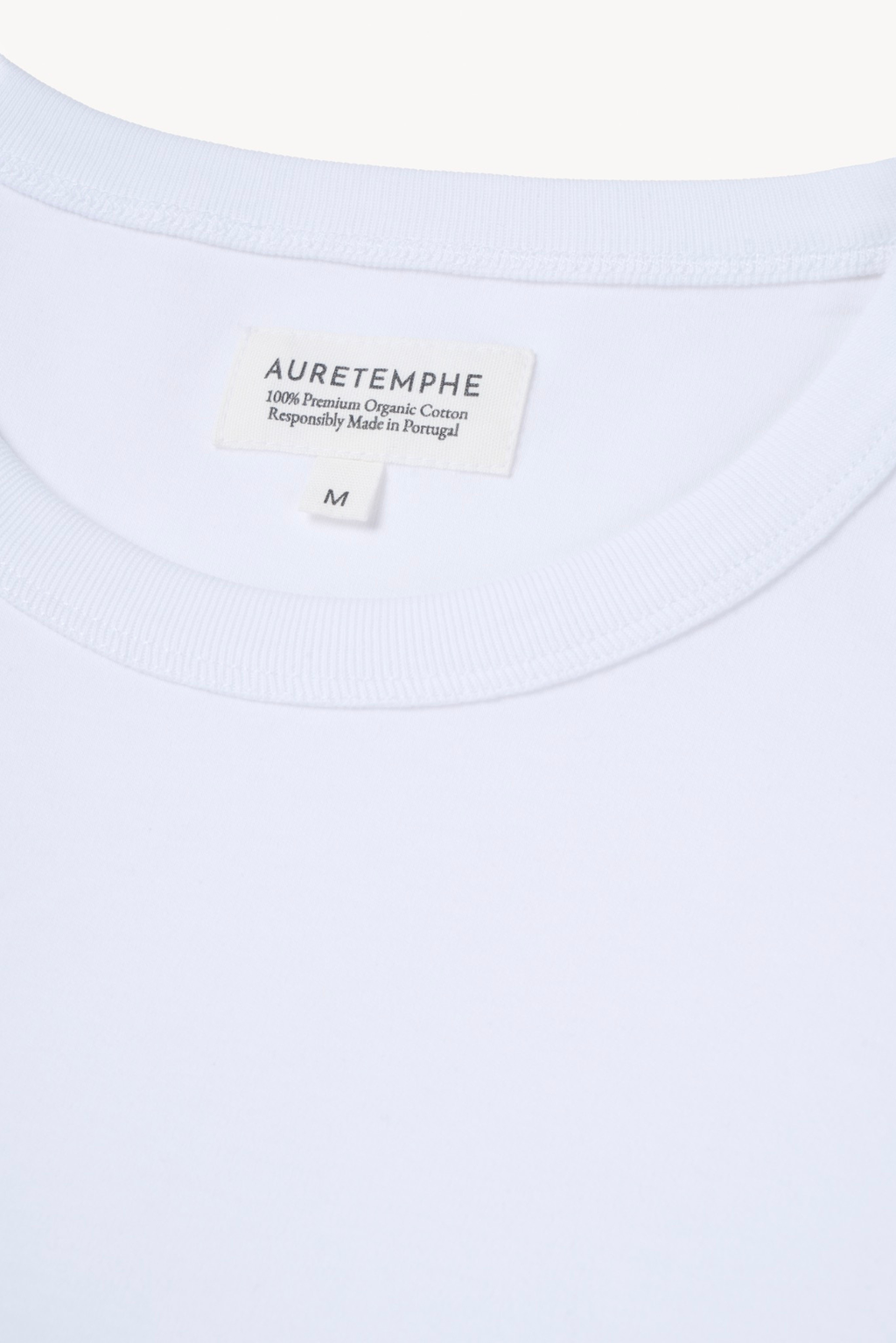 Detail view of AURETEMPHE white short sleeve t-shirt featuring its organic cotton main label.