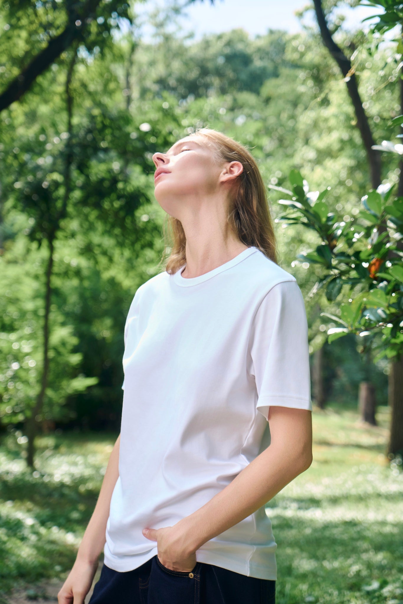Female model enjoying the sunlight, wearing AURETEMPHE white organic cotton short sleeve t-shirt.