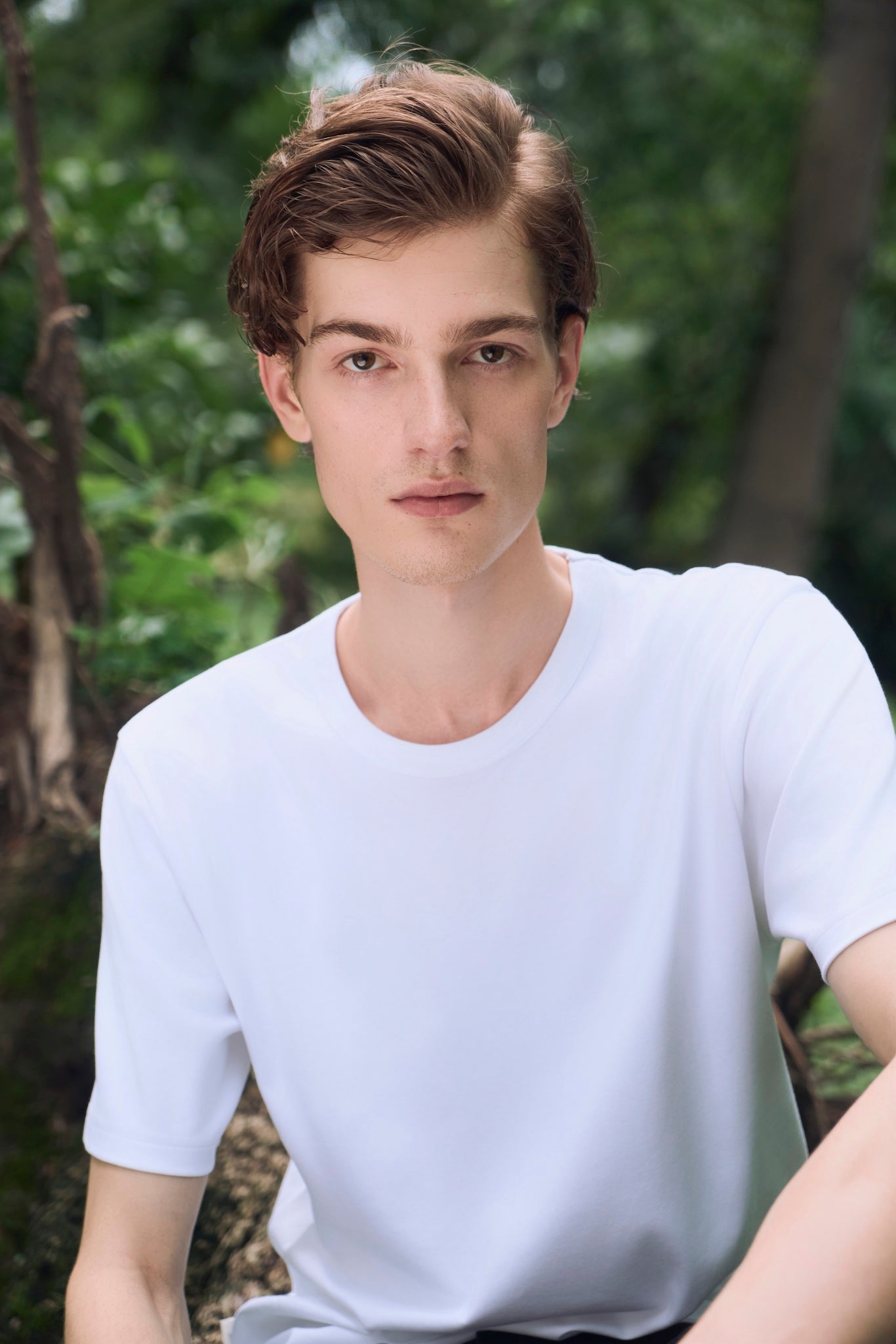 Male model looking straight ahead with a calm expression, wearing AURETEMPHE white organic cotton short sleeve t-shirt.