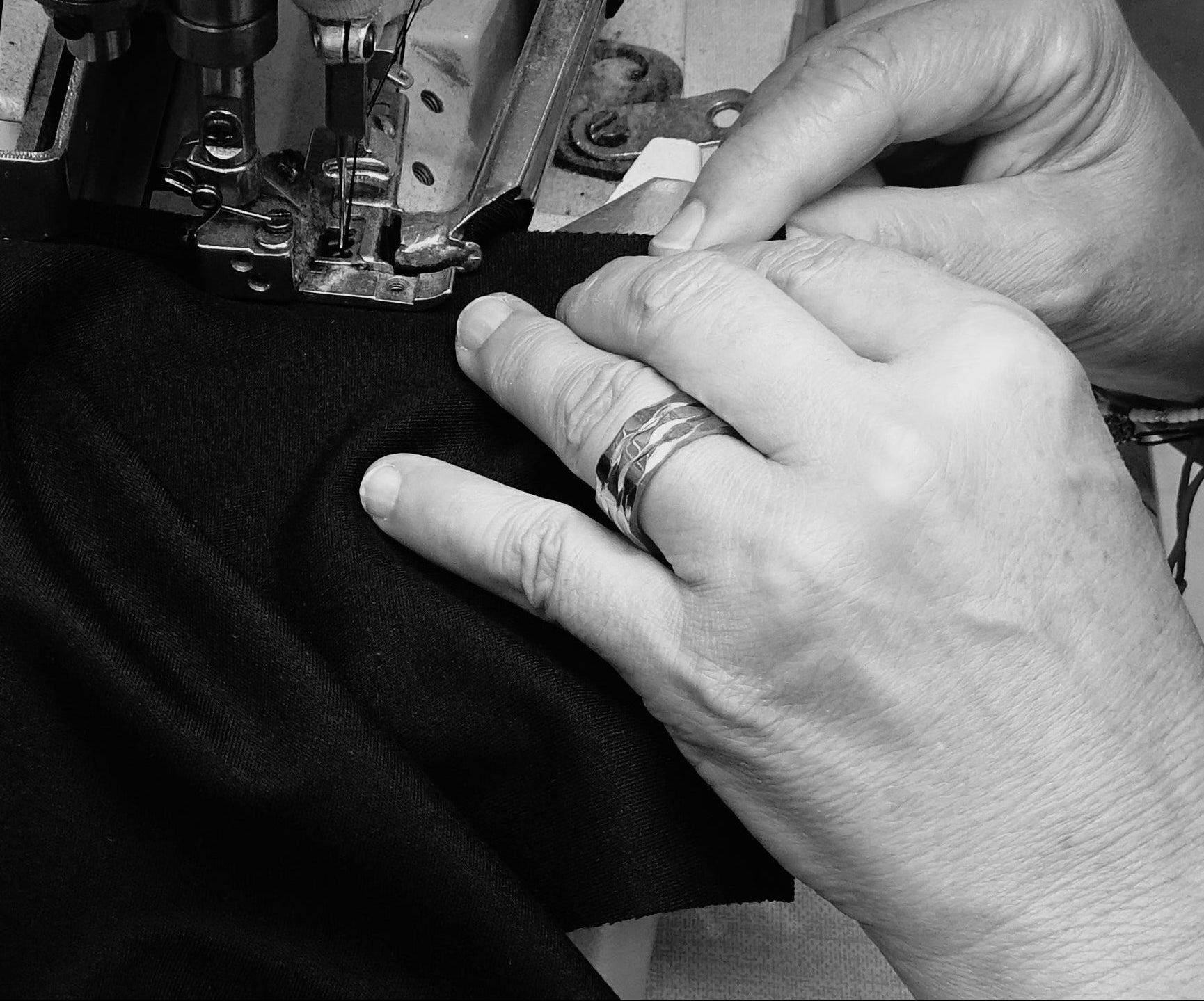 Detail of Portuguese craftsmanship: artisan performing precise stitching on an AURETEMPHE garment.
