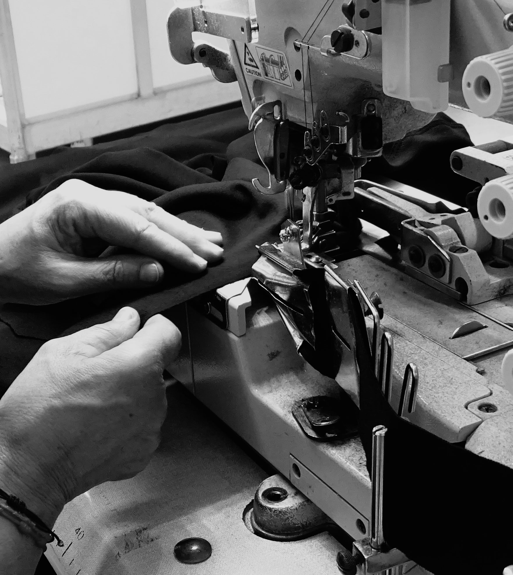 Detail of Portuguese craftsmanship: artisan sewing an AURETEMPHE garment with attention to detail.