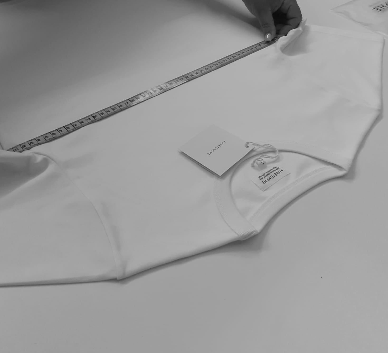 Detail of Portuguese craftsmanship: artisan checking the dimensions of a completed AURETEMPHE garment for quality assurance.