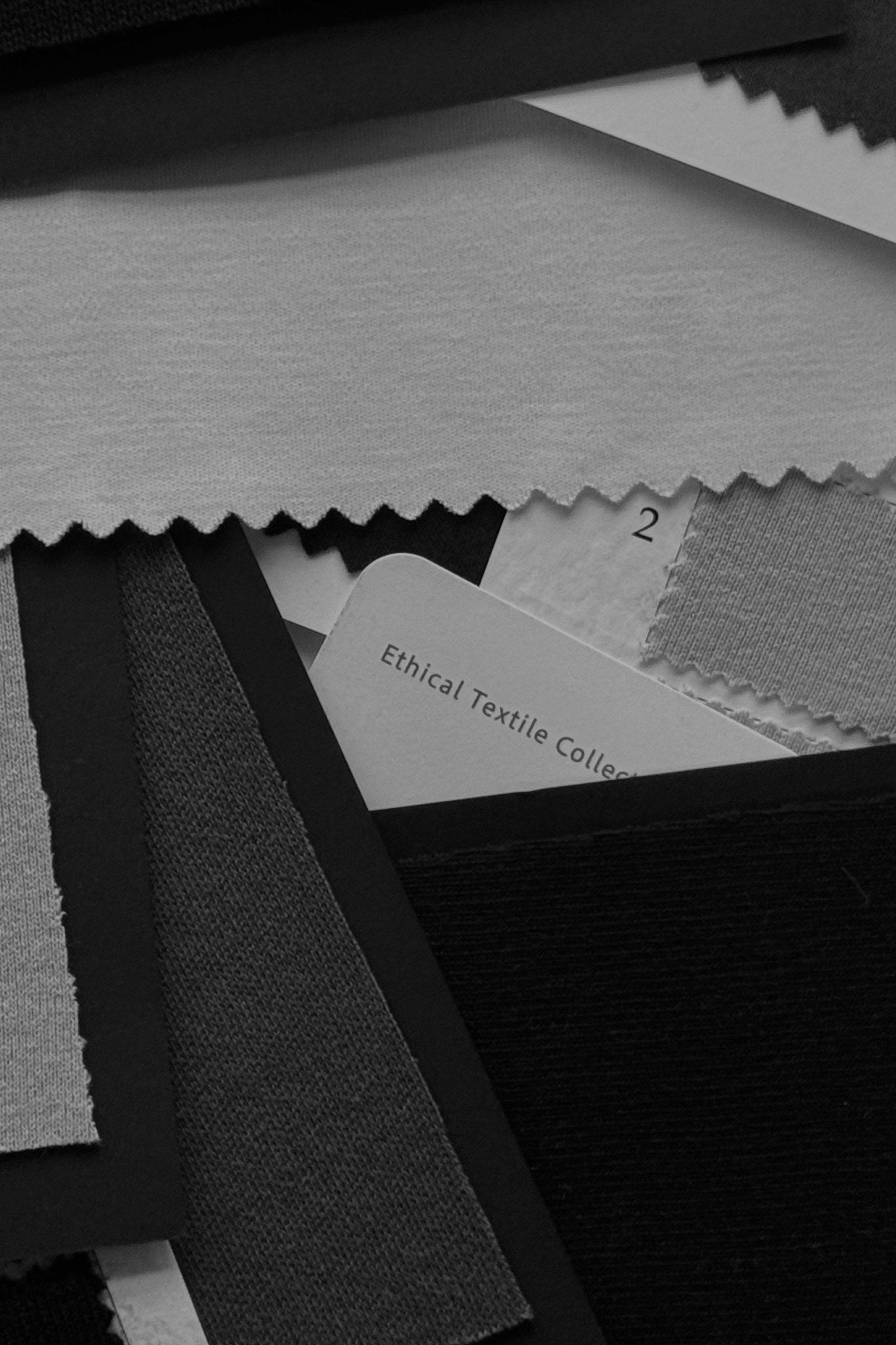 Various organic cotton fabrics stacked on a table.